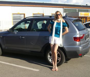 blonde Frau mit langen Beinen vor BMW